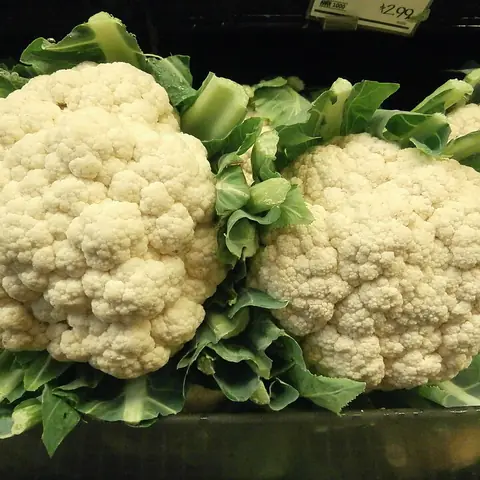Two white cauliflowers with green leaves