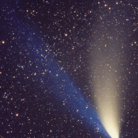 A comet with a long bright tail among the stars