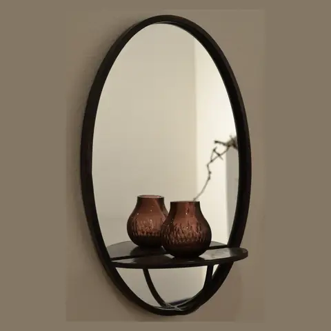An oval mirror with a dark frame on a wall