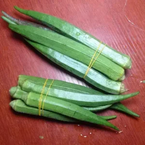 Long green okra pods on a red table