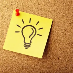 A yellow square sticky note pinned to a cork board