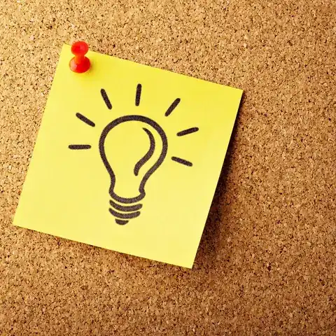 A yellow square sticky note pinned to a cork board